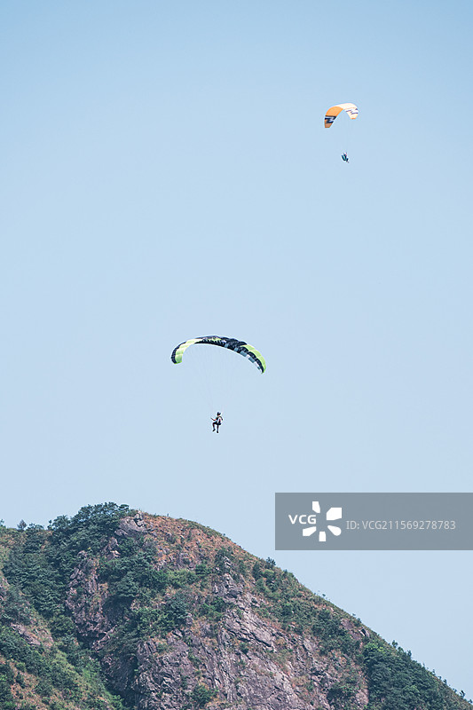 在晴朗的蓝天下滑翔伞的低角度视角-山脉前景图片素材