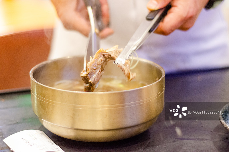 厨师正用剪刀剪下牛骨头上的肉图片素材