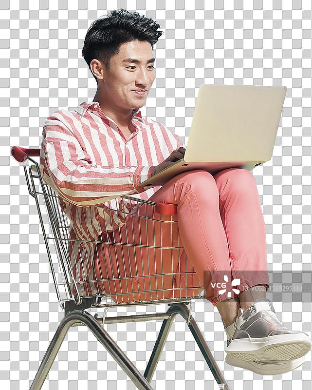 青年男人坐在购物车里用笔记本电脑图片素材