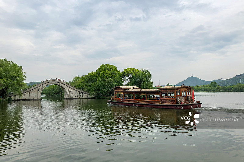 浙江杭州萧山区湘湖上的游船正要穿过湖上的拱桥图片素材