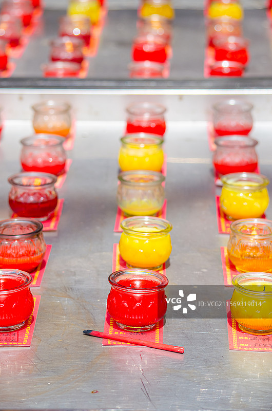中国宗教用品拍摄主题，桌子上摆放着多样的彩色的正在待售的玻璃瓶酥油蜡烛，户外白昼无人图像摄影图片素材