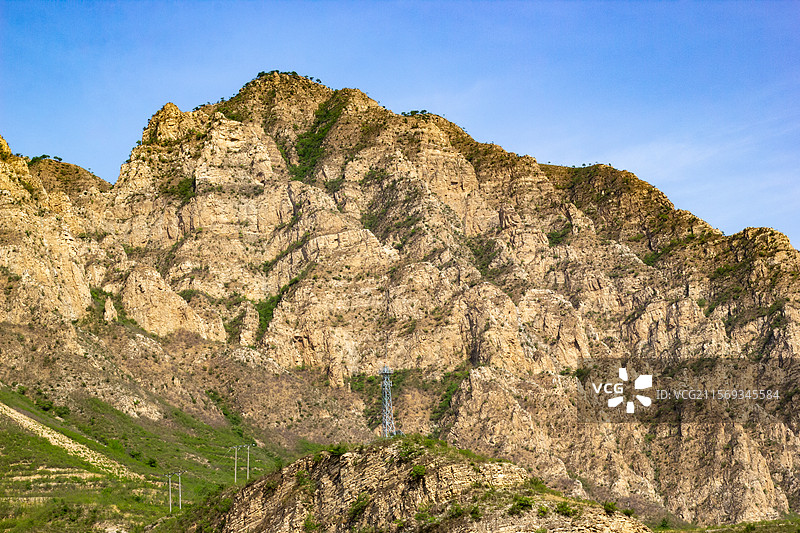 高大的风化沉积岩山体和的电网电力传输铁塔图片素材