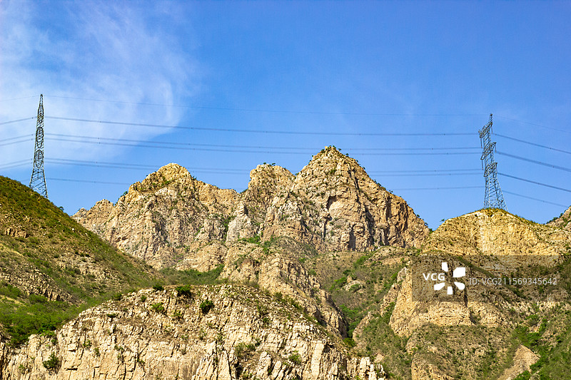 风化沉积岩山顶上的电网电力传输铁塔图片素材