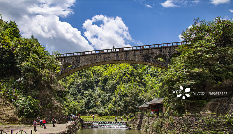 蓝天白云下4A旅游景区侠天下里大跨距拱渠桥下溪边小路上游人悠闲惬意地旅玩着图片素材