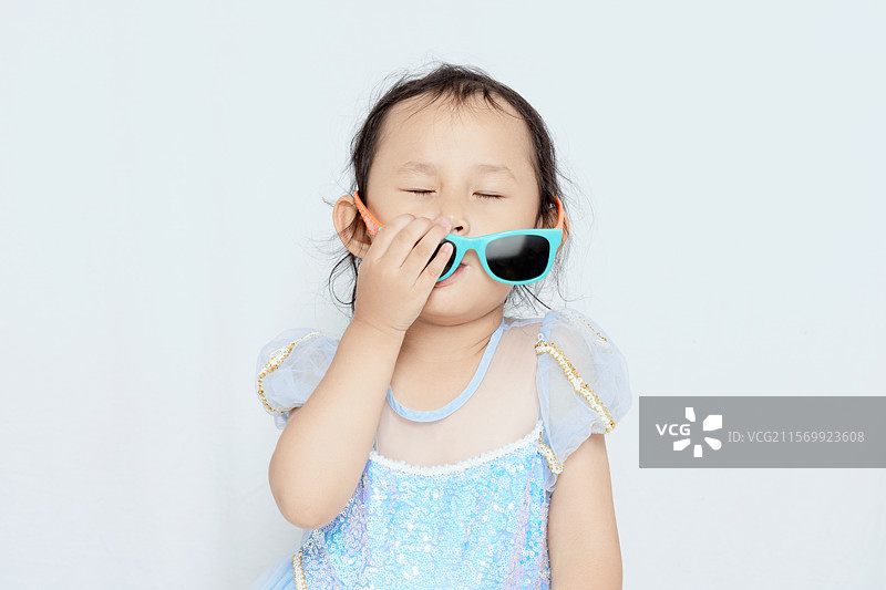 穿着蓝色公主裙带着墨镜的3岁女孩图片素材