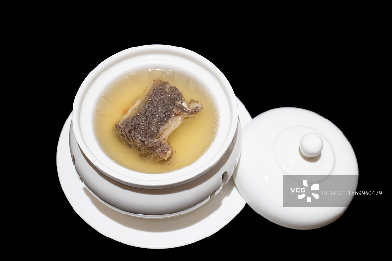 黑色背景白色餐具里的一段排骨和汤料图片素材