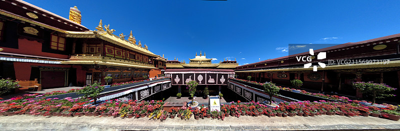 西藏拉萨大昭寺金顶在蓝天映衬下熠熠生辉红墙庄重古朴殿前繁花似锦尽显藏传佛教寺院的庄严与绚丽。图片素材