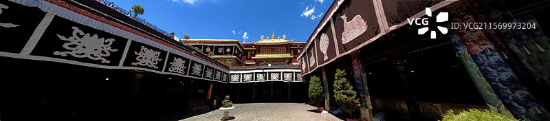 西藏拉萨大昭寺金顶在蓝天映衬下熠熠生辉红墙庄重古朴殿前繁花似锦尽显藏传佛教寺院的庄严与绚丽。图片素材