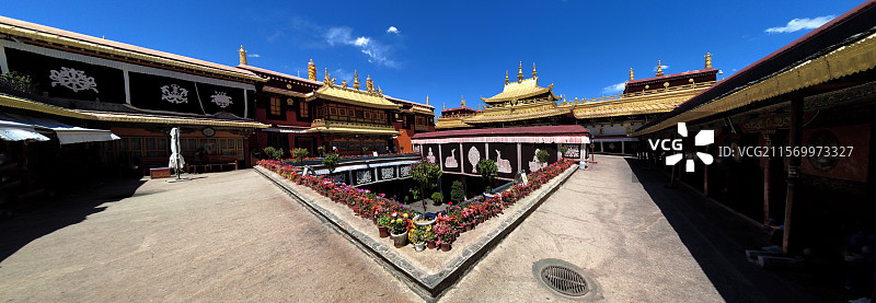 西藏拉萨大昭寺金顶在蓝天映衬下熠熠生辉红墙庄重古朴殿前繁花似锦尽显藏传佛教寺院的庄严与绚丽。图片素材