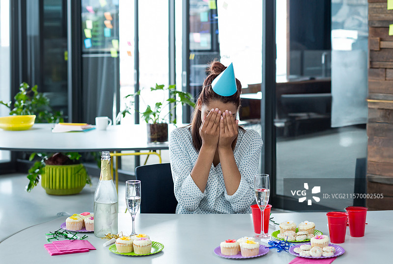 霜冻杯子蛋糕和闪亮饮料摆放在现代办公桌上，旁边有五颜六色的餐巾纸。图片素材