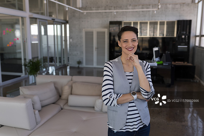 米色皮革沙发组合放置在办公室的抛光混凝土地板上，周围有玻璃隔断。图片素材