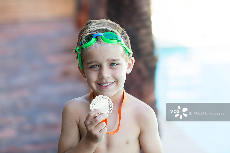 银牌与橙色丝带和绿色护目镜静静地放在泳池甲板上，留有空白空间。图片素材