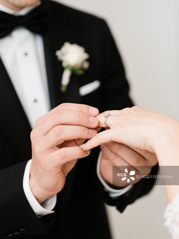 新郎给新娘戴上婚戒的手部特写图片素材