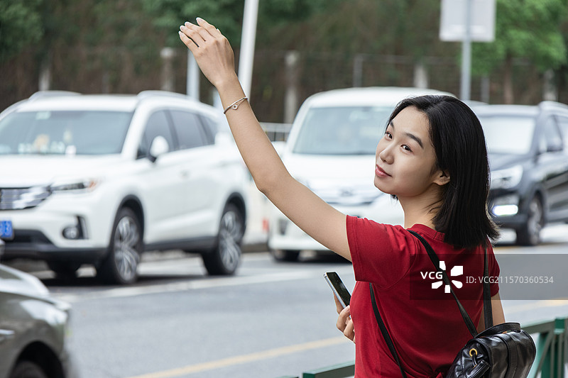 城市街头打网约车的中国年轻女子图片素材