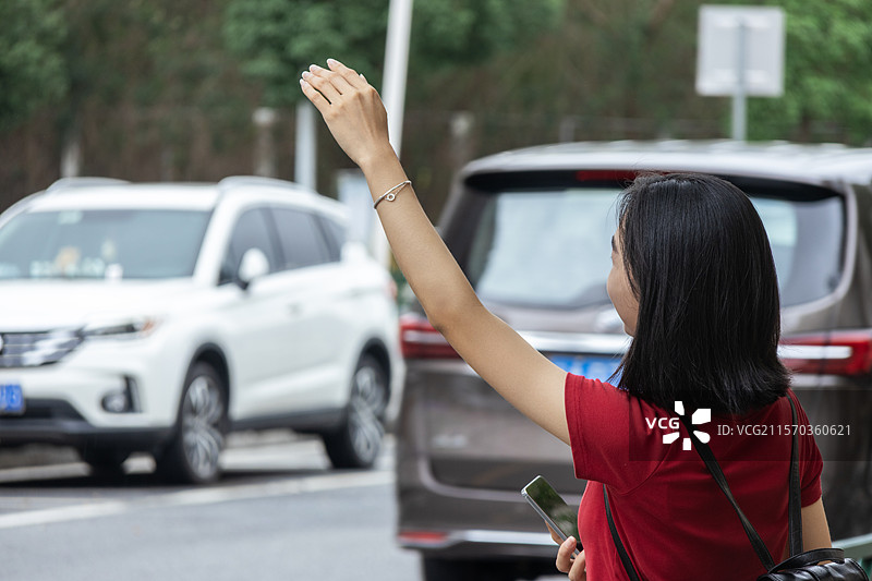 城市街头打网约车的中国年轻女子图片素材
