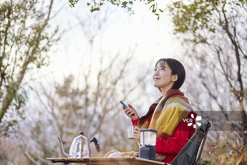 日本女性在冬季山脉中享受户外时使用智能手机。图片素材