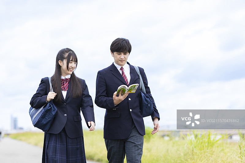 男生和女生高中生一边走一边学习图片素材