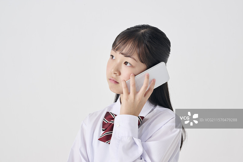 日本初中女生在白色背景下打电话图片素材