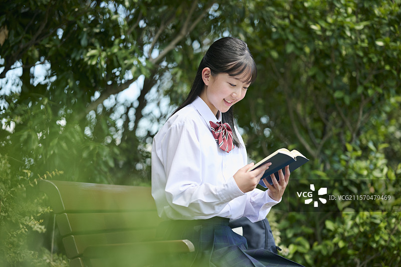 初中女孩在公园里阅读一本书图片素材