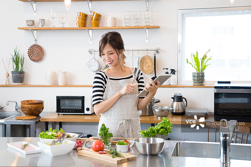 年轻女性使用平板电脑做饭图片素材