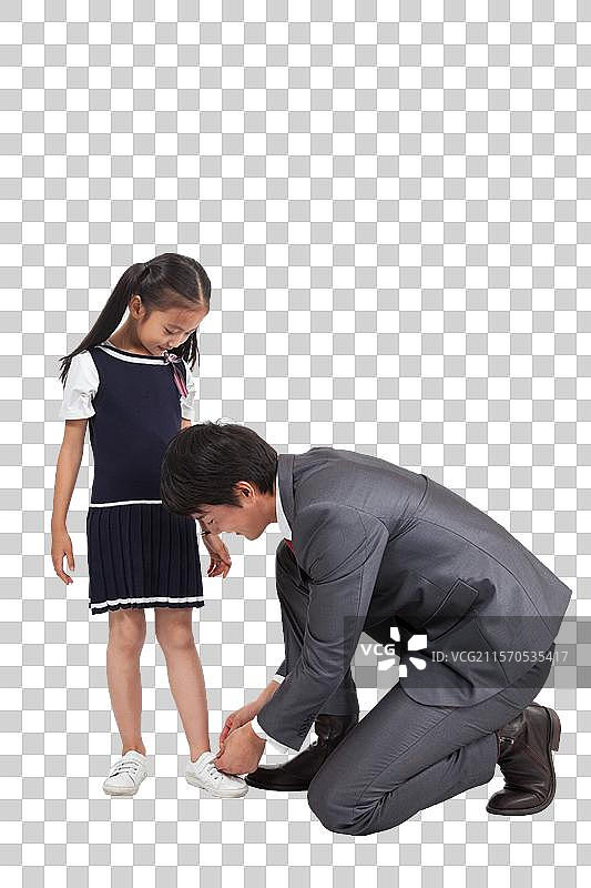 棚拍商务装年轻父亲为穿裙子的小女孩系鞋带图片素材
