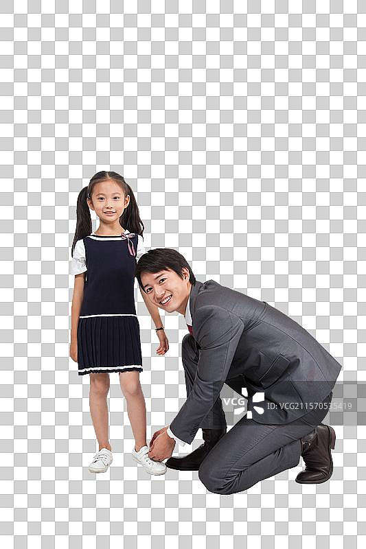 棚拍商务装年轻父亲为穿裙子的小女孩系鞋带图片素材