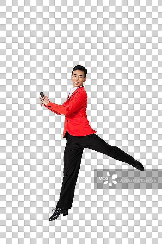 棚拍穿红色西装的年轻男人拿着手机跳舞图片素材