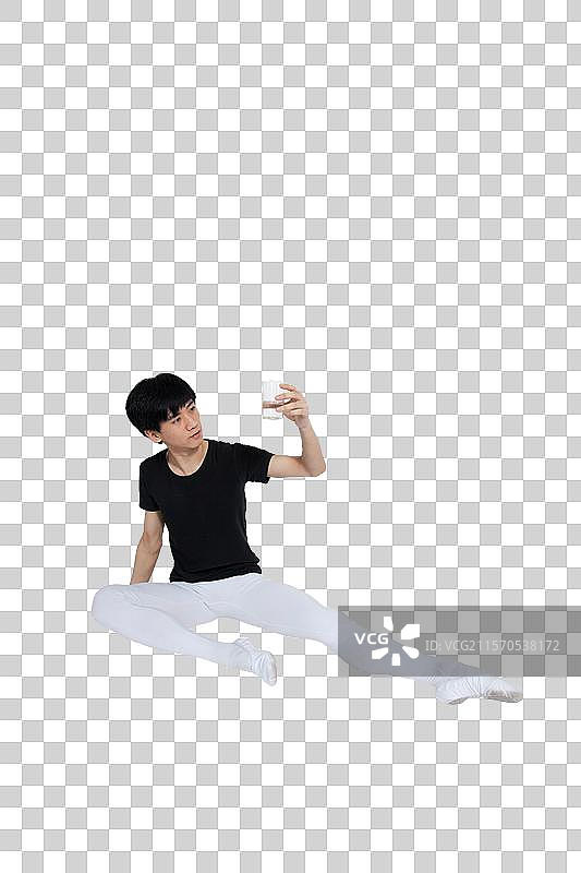 棚拍年轻的芭蕾舞男演员坐在地上喝水休息图片素材
