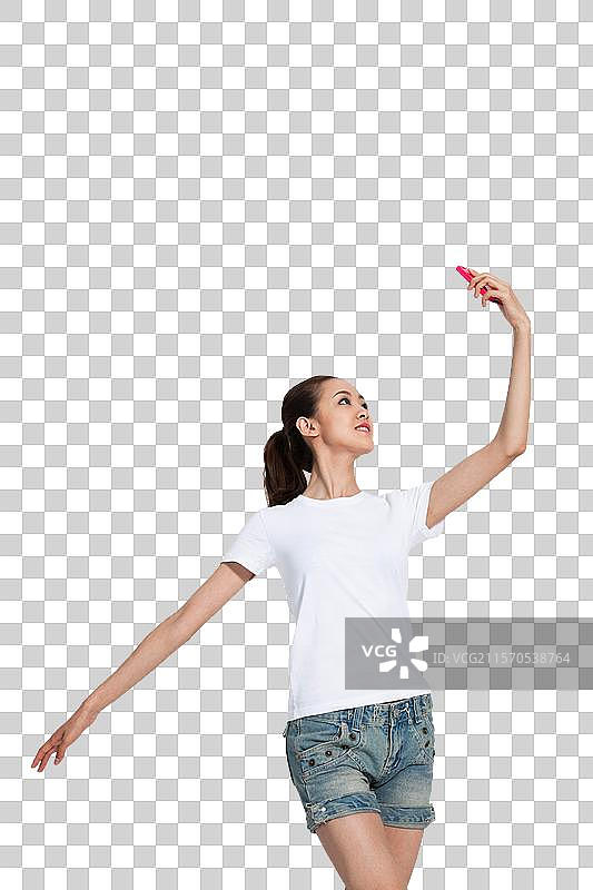 棚拍年轻女人拿着手机跳舞图片素材