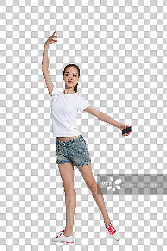 棚拍年轻女人拿着手机跳舞图片素材