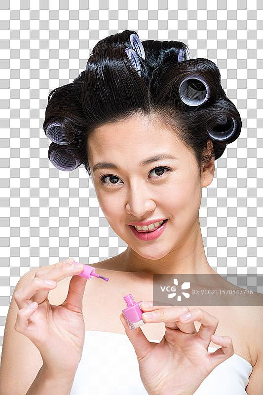 棚拍戴着卷发棒的年轻女人涂指甲油图片素材