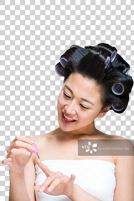 棚拍戴着卷发棒的年轻女人涂指甲油图片素材