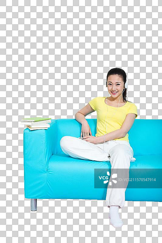 棚拍年轻女人坐在沙发上听音乐图片素材