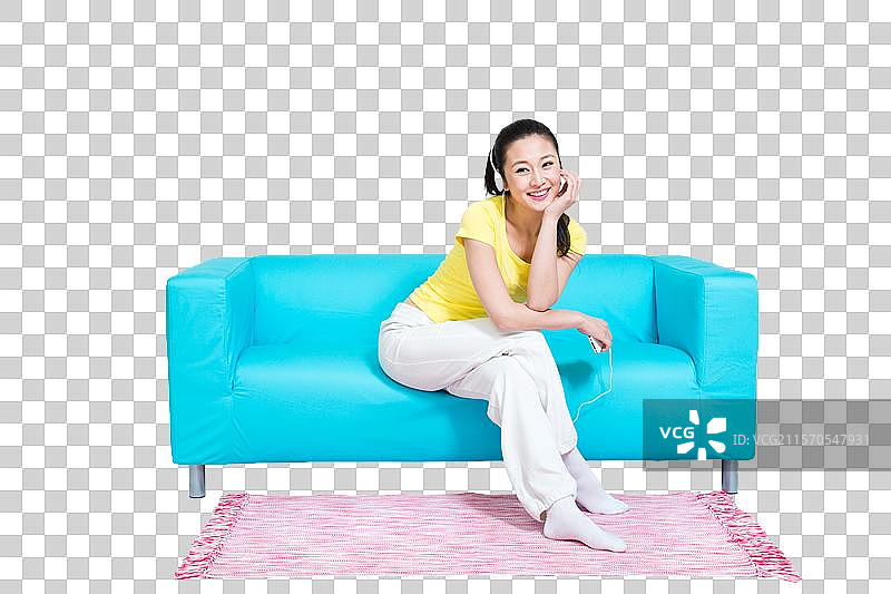 棚拍年轻女人坐在沙发上听音乐图片素材