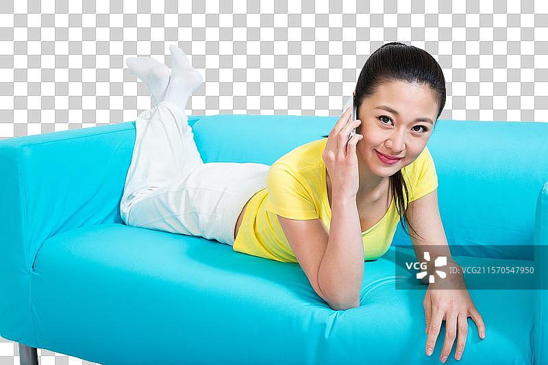 棚拍年轻女人趴在沙发上玩手机图片素材