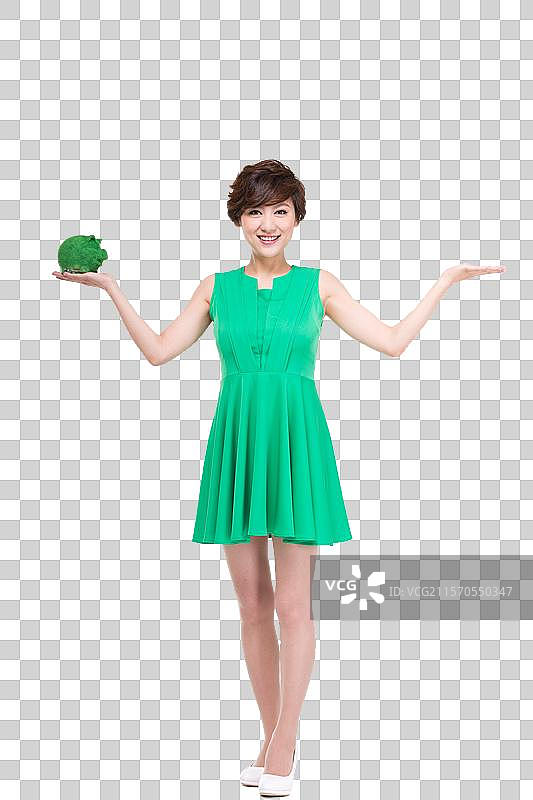 穿绿色裙子的年轻女人拿着绿色小猪存钱罐图片素材