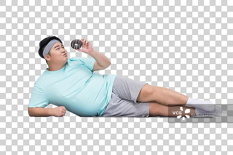 肥胖的青年男子拿着甜甜圈做运动图片素材