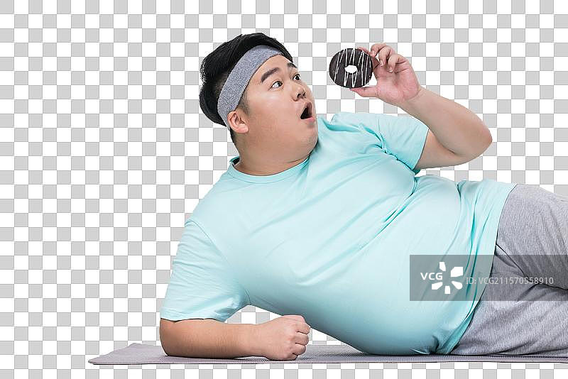 肥胖的青年男子拿着甜甜圈做运动图片素材