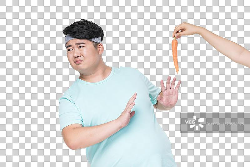 肥胖的青年男子拒绝吃胡萝卜图片素材