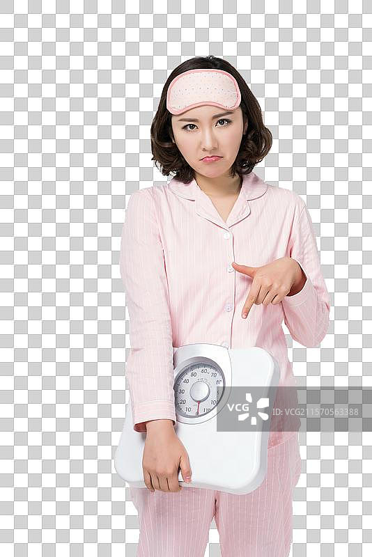 穿着睡衣的年轻女子拿着体重秤图片素材