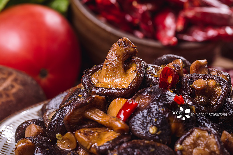 搭配着蔬菜和干辣椒的桌子上摆放着一个装满卤香菇的盘子.jpg图片素材