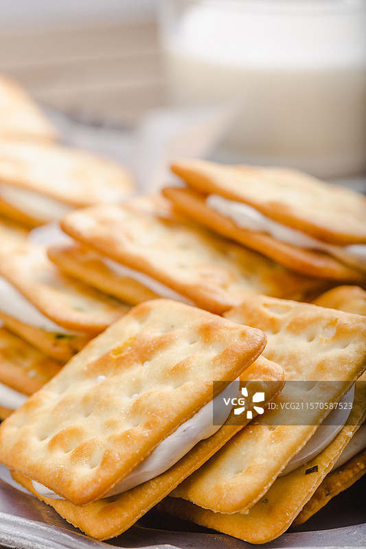 早点饼干叠在一起并且后方有虚化的牛奶在杯子里图片素材