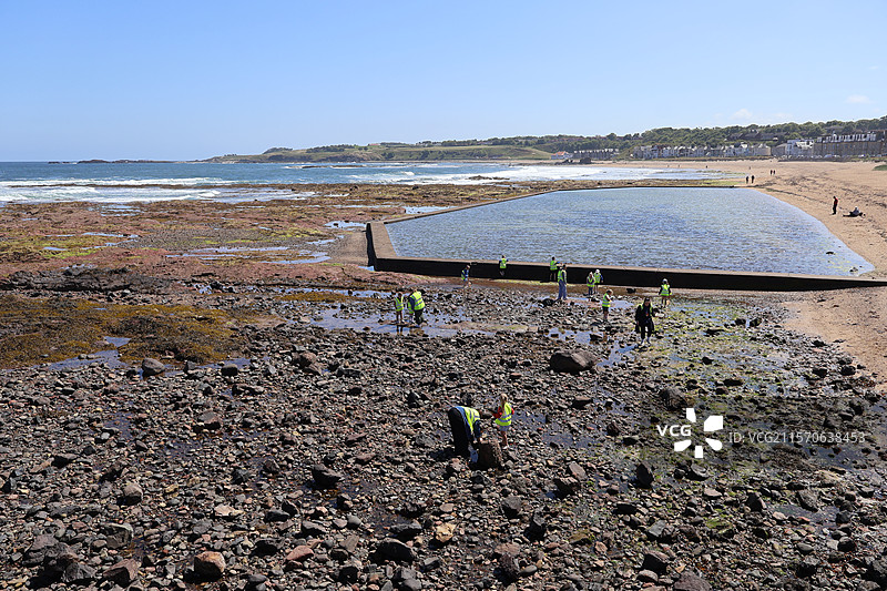 小朋友在英国北贝里克海滩滩涂上的户外寻宝活动图片素材