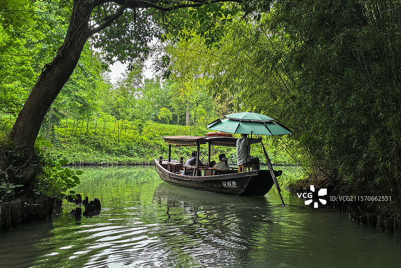 西溪湿地公园里的河水幽绿，蜿蜒曲折，绿树成荫，一艘摇撸船正荡波水面，很是悠闲图片素材