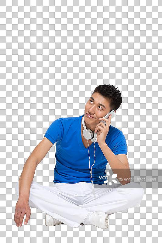 棚拍时尚活力年轻人盘着腿坐在地上打手机图片素材