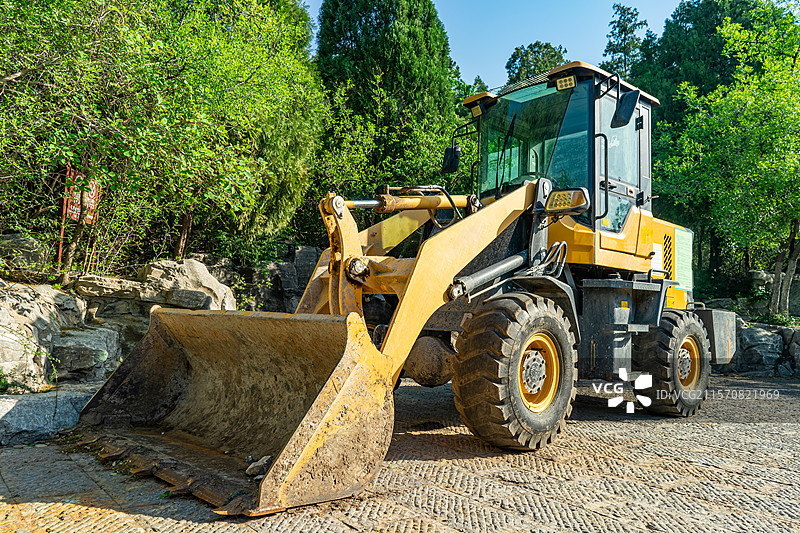 中国建筑业设备用品拍摄主题，高山下面停泊着一辆的推土机挖掘机机器，户外白昼无人图像摄影图片素材