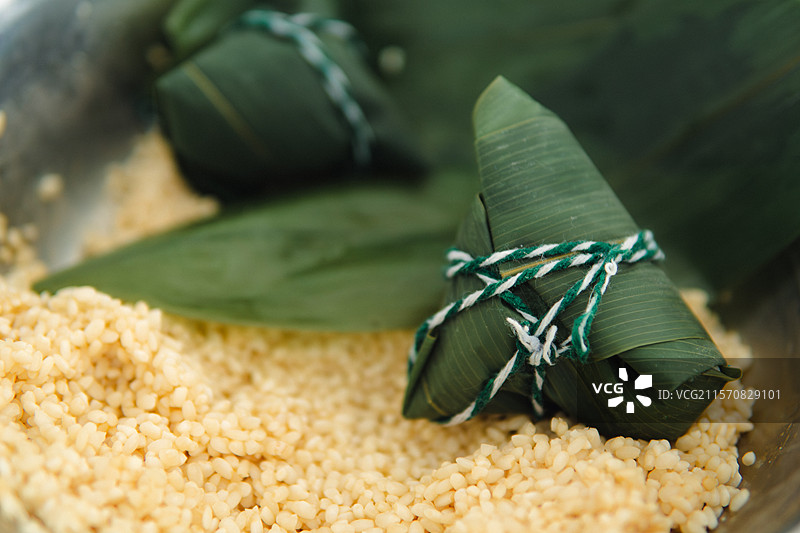 放在糯米上的刚包好的粽子特写，端午节图片素材