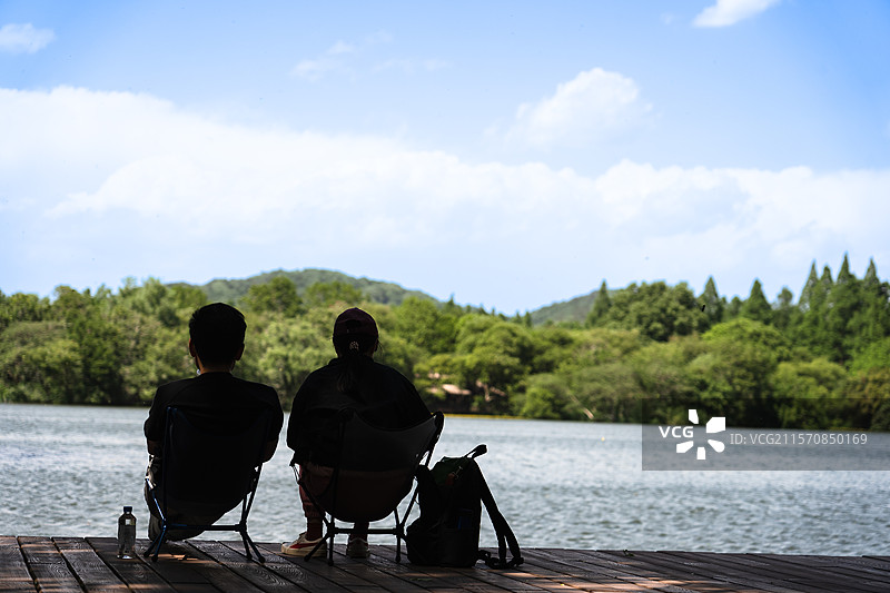 西湖边坐着放松的情侣图片素材