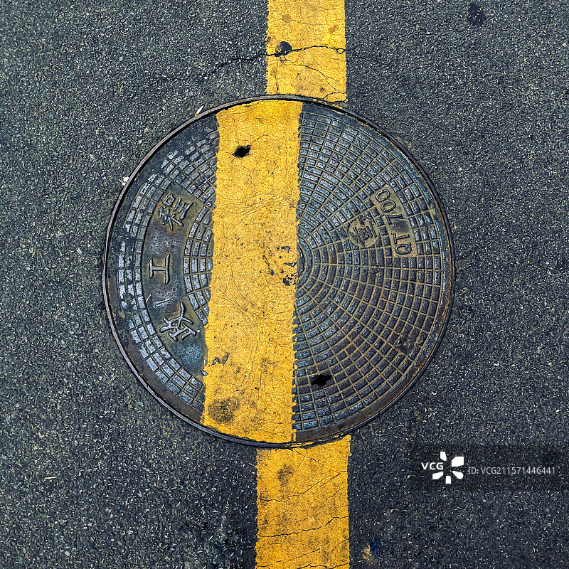 黄色双线间的圆形井盖图片素材