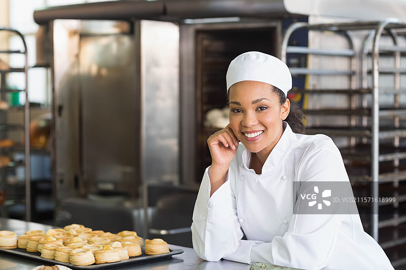 烘焙托盘上放着金黄色的糕点，置于面包店厨房的不锈钢台面上图片素材